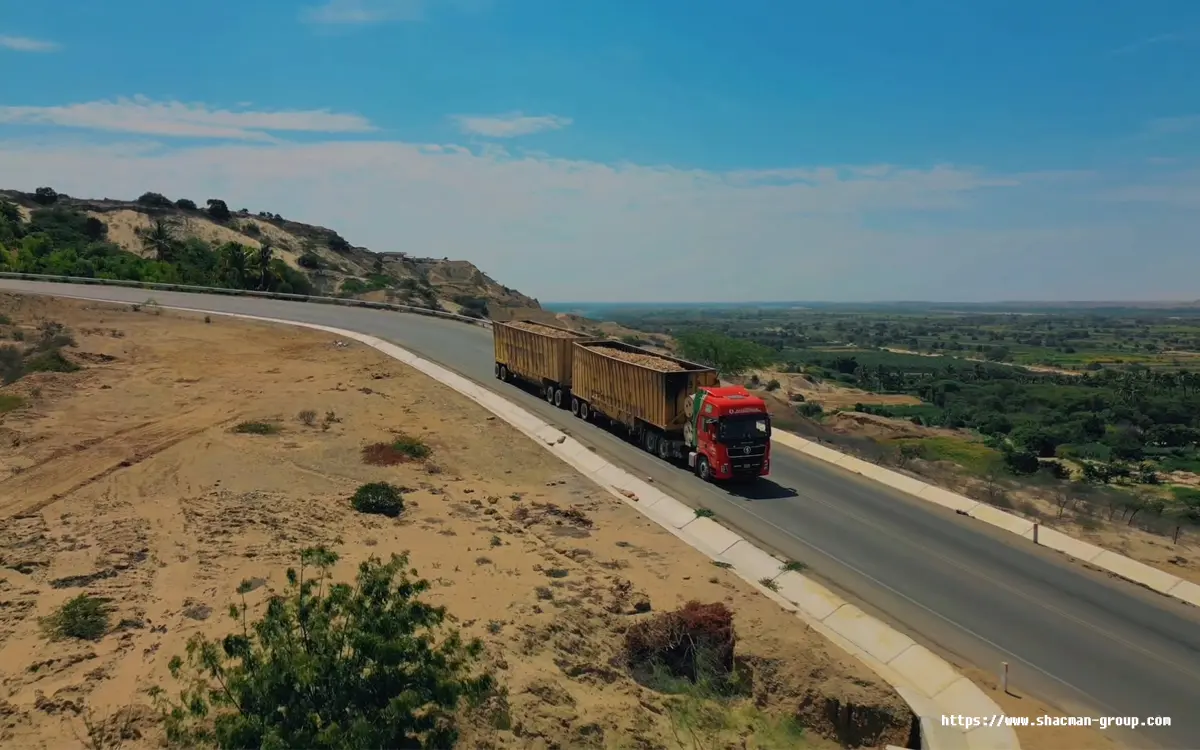 Red Shacman truck with two side dump trailers transporting ore in Libya