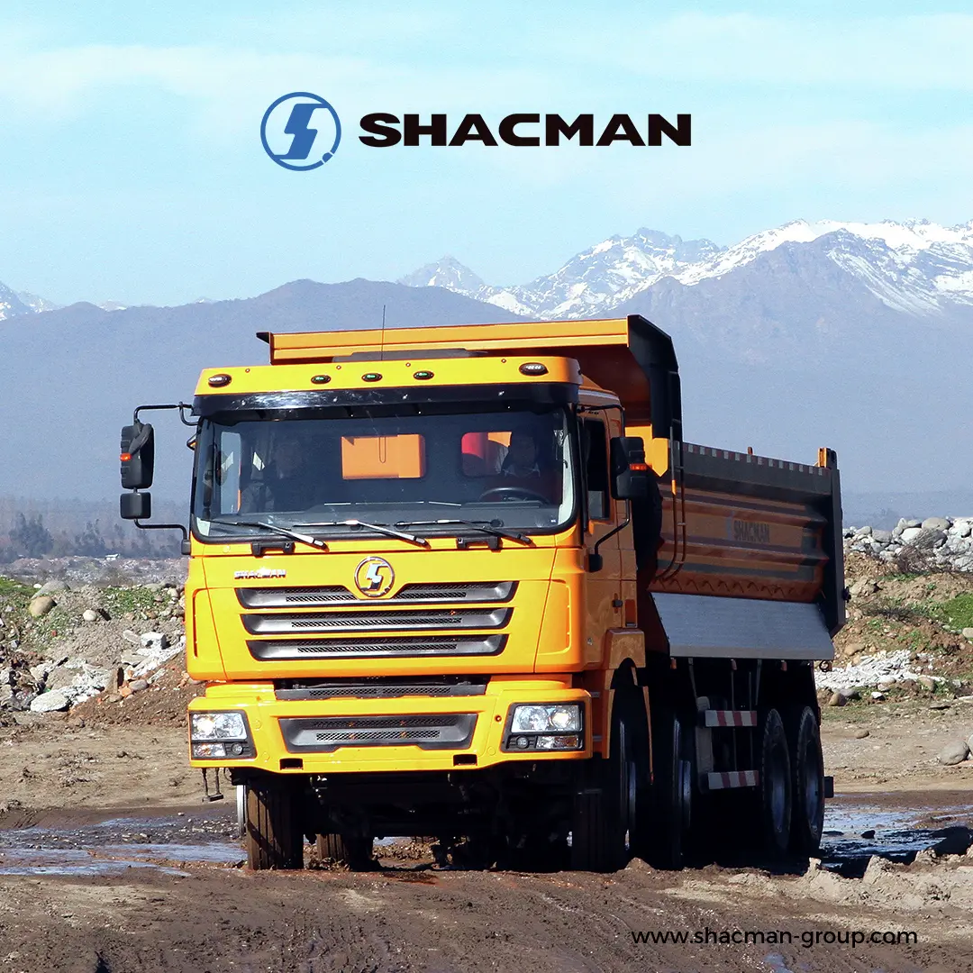 Yellow SHACMAN tipper truck driving on a muddy and rough terrain road.